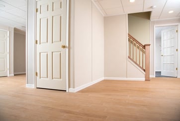 Finished basement with a door and stairs in view.