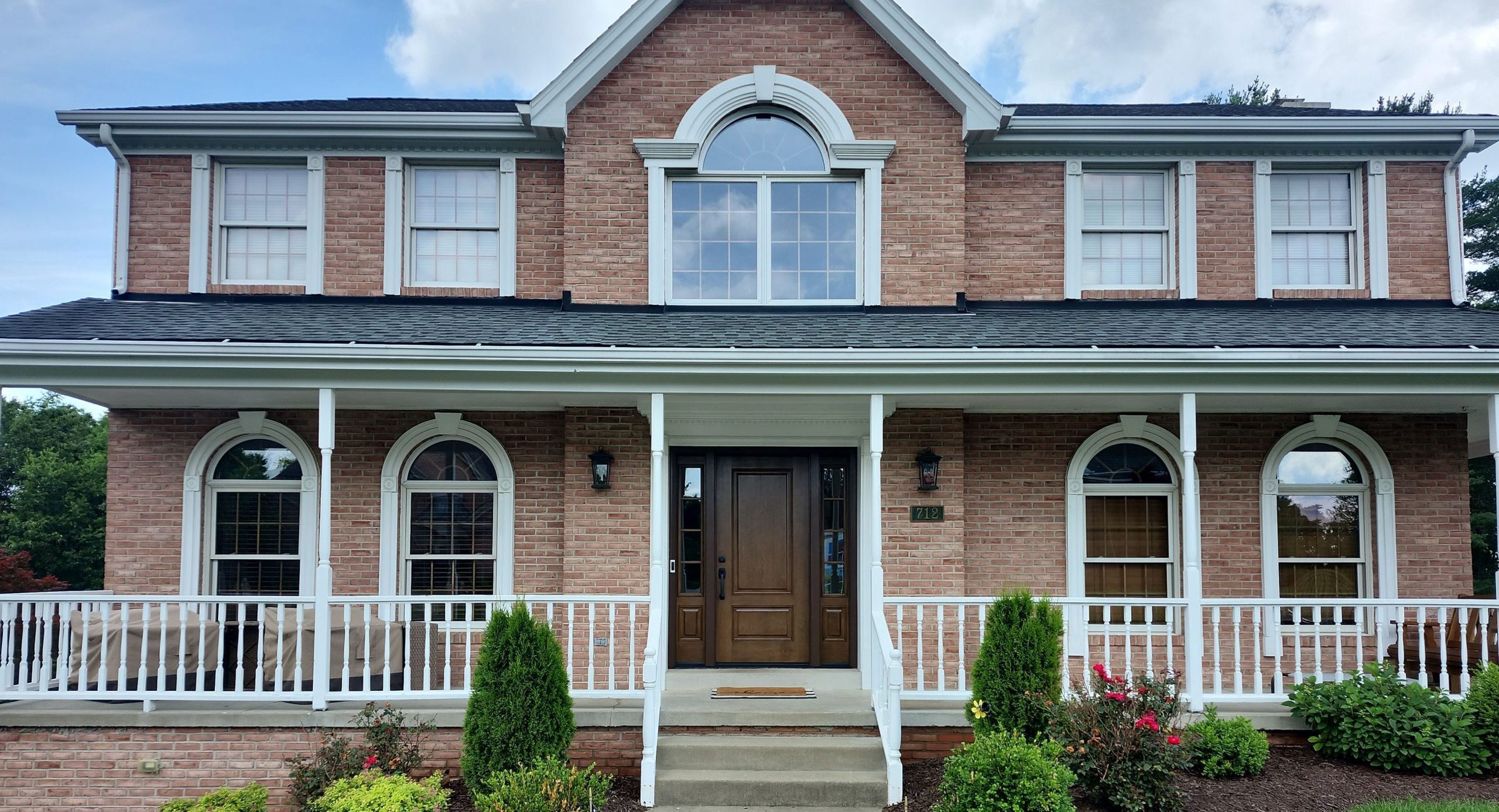 Two-story brick home with 8 double hung windows and a brown entry door.
