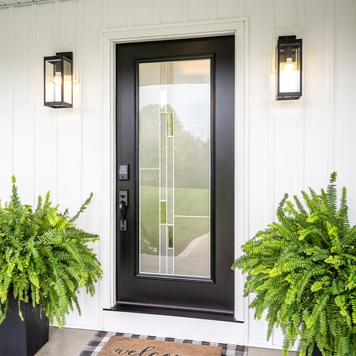 Black painted steel entry door with full glass between two lanterns