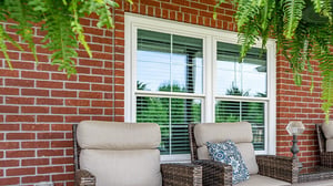 Patio seating in front of white windows on a brick home