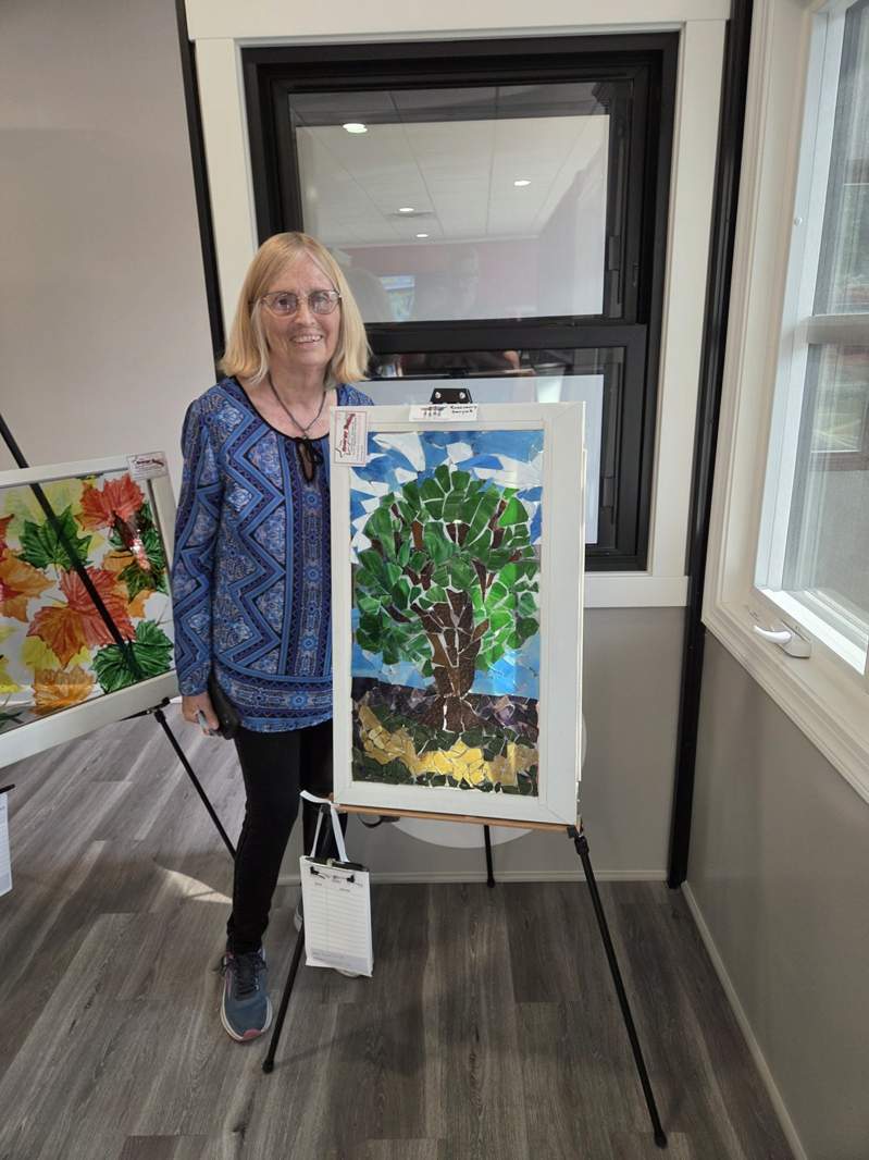 Community member with tree mosaic on a reclaimed window at the October 1, 2026 Design Center event