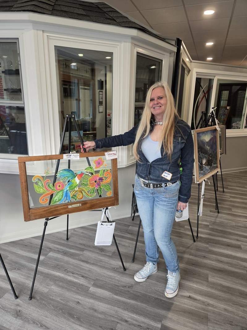 Community member with colorful bird and flower window art at the October 1, 2026 Design Center event